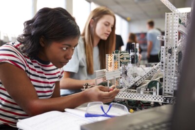 Two Female College Students Building Machine In Science Robotics Or Engineering Class