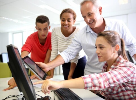 Teacher views screens in tech lab with students